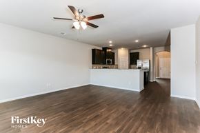 Rosharon house for rent - A spacious room with a ceiling fan and wooden flooring.
