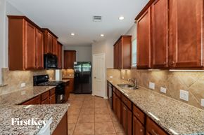 Baytown house for rent - A kitchen with brown cabinets and a granite countertop.