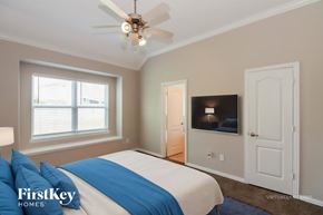 Baytown house for rent - A bedroom with a bed, a ceiling fan, and a television.
