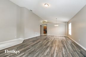 Apopka house for rent - A spacious room with wooden flooring and a light fixture hanging from the ceiling.
