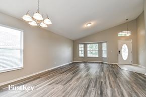 Apopka house for rent - A spacious room with wooden flooring and a chandelier.
