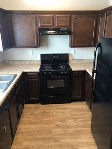 El Paso apartment for rent - A black stove and oven in a kitchen with wooden cabinets.