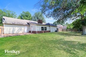 Memphis house for rent - A house with a white exterior and a grey roof is surrounded by a grassy yard.