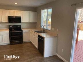 Thornton house for rent - a kitchen with white cabinets and a black stove and a sink