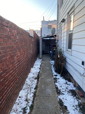 Reading apartment for rent - A narrow alley with a brick wall on one side and a white house on the other.