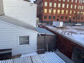 Reading apartment for rent - A view of a snowy rooftop with a white house and a red brick building in the background.