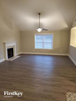 Gainesville house for rent - an empty living room with a fireplace and a ceiling fan