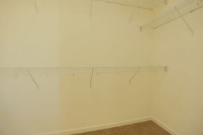 Livermore house for rent - A room with a white wall and a brown floor with clothes hangers.