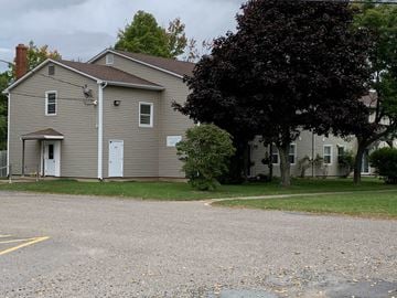 Kentville apartment for rent - A grey house with a tree in front.