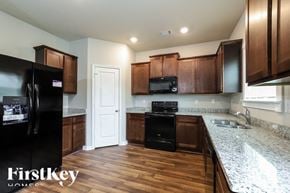 Pendergrass house for rent - a kitchen with wooden cabinets and granite counter tops and black appliances