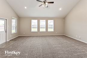 Humble house for rent - A spacious room with a carpeted floor, a ceiling fan, and three windows.