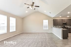 Humble house for rent - A spacious room with a ceiling fan and a kitchen area in the background.