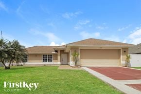 Lehigh Acres house for rent - a beige house with a lawn and a driveway