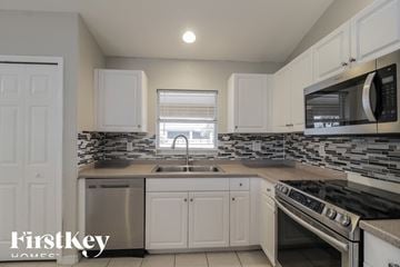 Lehigh Acres house for rent - a kitchen with white cabinets and stainless steel appliances