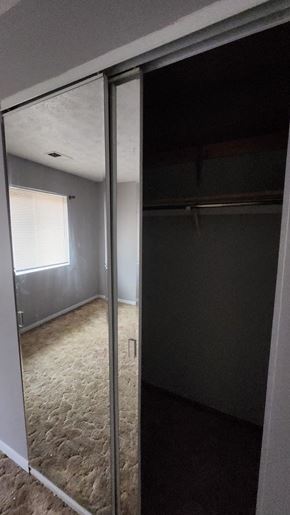 Cincinnati apartment for rent - A room with a carpeted floor and a closet with a mirror.