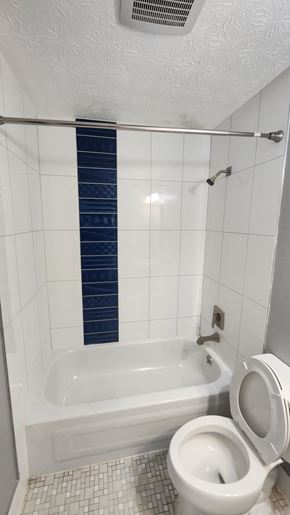 Cincinnati apartment for rent - A white toilet in a bathroom with a blue and white tiled shower.