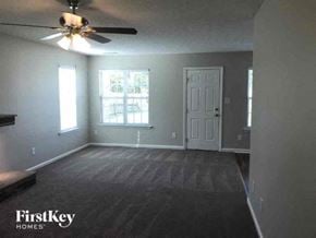 Charlotte house for rent - an empty living room with a ceiling fan and a white door