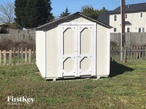 Charlotte house for rent - a small white shed in the grass next to a fence