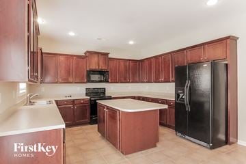 Charlotte house for rent - A kitchen with wooden cabinets and a black refrigerator.