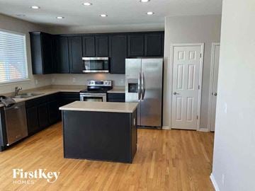 Thornton house for rent - a kitchen with black cabinets and a stainless steel refrigerator