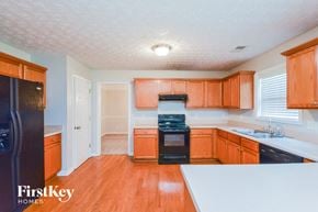 Lithonia house for rent - a kitchen with wooden cabinets and black appliances and white counter tops