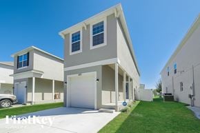 Kissimmee house for rent - a beige and white house with a driveway and a lawn