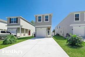 Kissimmee house for rent - a white and gray house with a driveway and grass