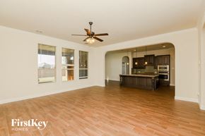 Aledo house for rent - an empty living room and kitchen with a ceiling fan