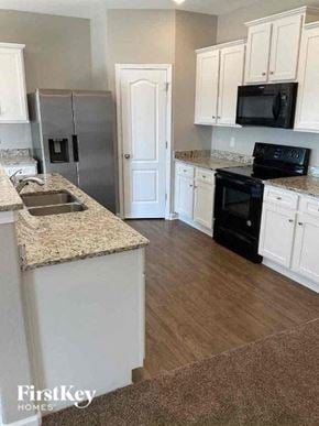 Charlotte house for rent - a kitchen with white cabinets and black appliances