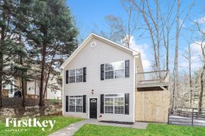 Gainesville house for rent - A house with a grey siding and a black door is surrounded by trees.