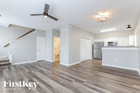 Gainesville house for rent - A spacious living room with a wood floor and a ceiling fan.