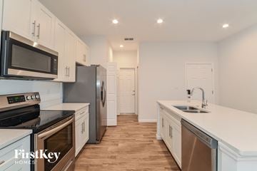 Deltona house for rent - a kitchen with white cabinets and stainless steel appliances and white counter tops
