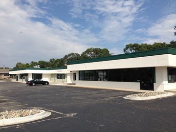 Lansing apartment for rent - a white building with a green roof and a parking lot