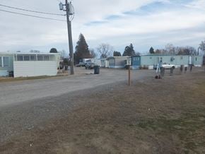 Grandview apartment for rent - A gravel road with a white car and a white van parked on the side.