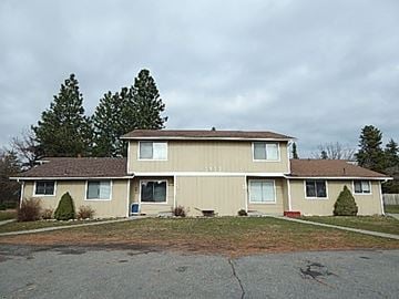 Coeur D' Alene house for rent - a beige house with a yard and trees