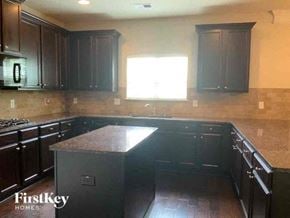 Conyers house for rent - an empty kitchen with black cabinets and a window