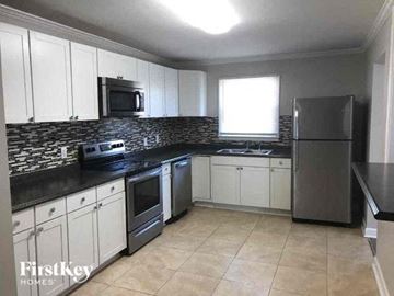 Gastonia house for rent - a kitchen with white cabinets and stainless steel appliances