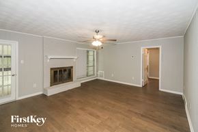 Memphis house for rent - an empty living room with a fireplace and a ceiling fan
