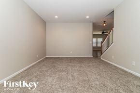 Dallas house for rent - A spacious room with a carpeted floor and a staircase in the background.