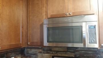 Hueytown house for rent - a kitchen with a stainless steel microwave and wooden cabinets