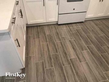 Fort Myers house for rent - a kitchen with a wooden floor and white cabinets
