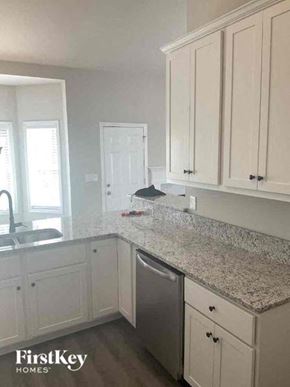 Dallas house for rent - a kitchen with white cabinets and a granite counter top