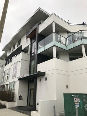 Vancouver apartment for rent - A white building with a green dumpster in front of it.