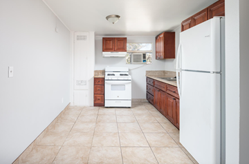 El Cajon apartment for rent - A kitchen with white appliances and brown cabinets.
