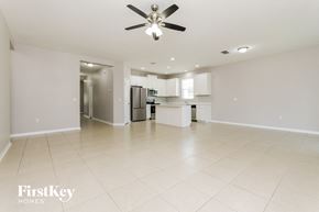 Orlando house for rent - A spacious, empty room with a ceiling fan and a kitchen area in the background.