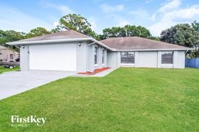 Palm Bay house for rent - A white house with a brown roof and a green lawn in front.