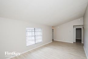 Palm Bay house for rent - A spacious empty room with a window and a door in the background.