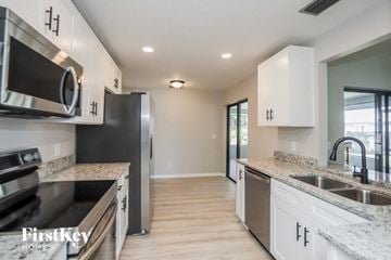 Palm Bay house for rent - A kitchen with a black refrigerator and stove top oven.