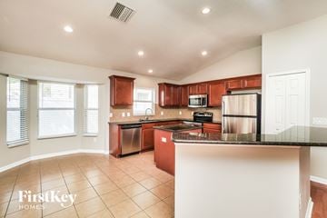 Land O Lakes house for rent - A kitchen with brown cabinets and a black counter top.