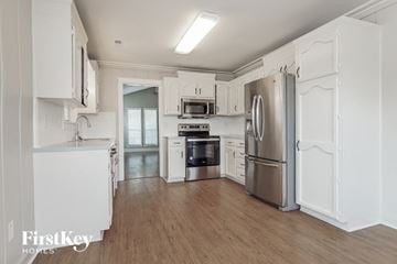 Helena house for rent - A kitchen with white cabinets and a stainless steel refrigerator.